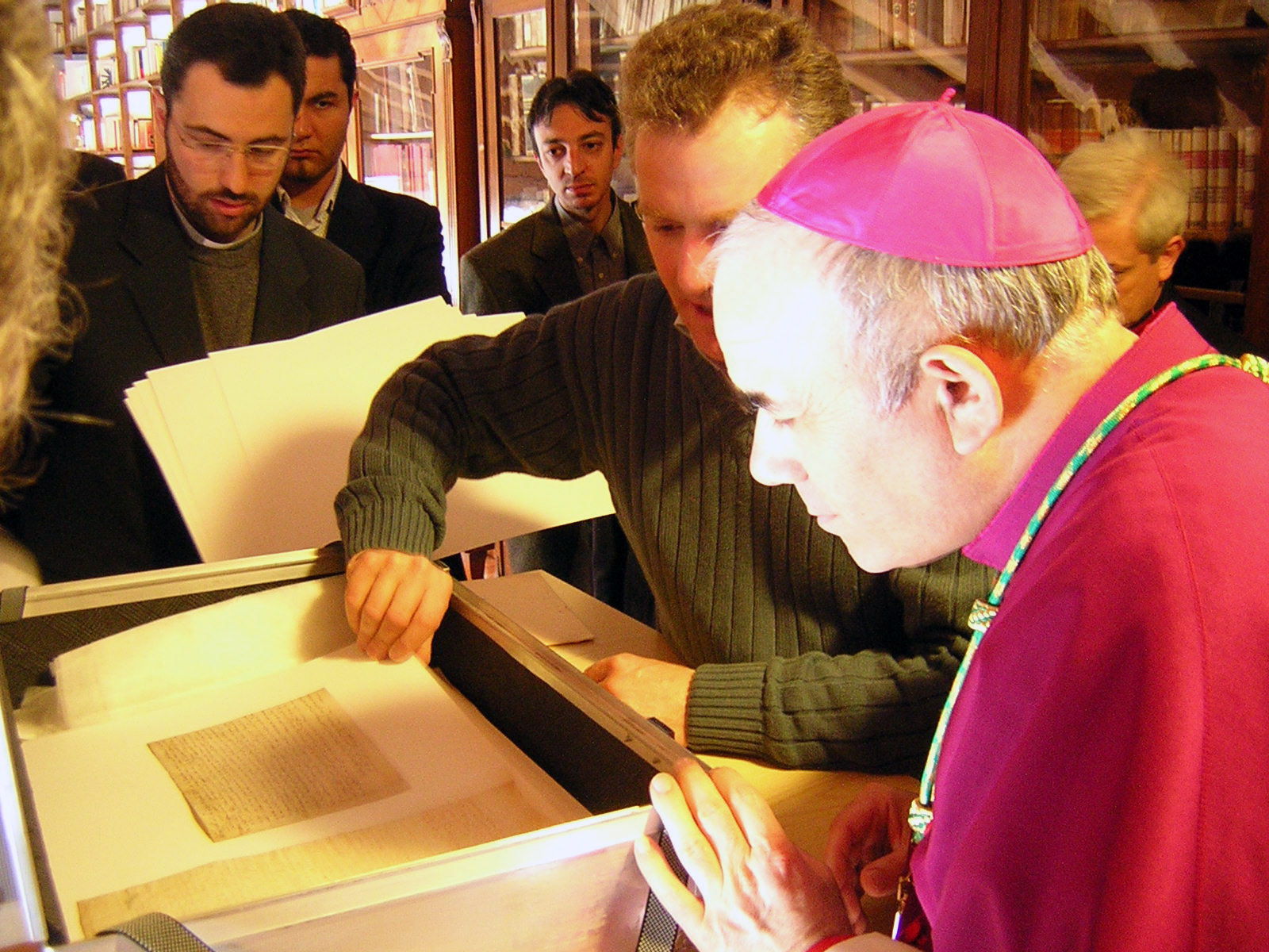 Il Vescovo osserva con iteresse le antiche pergamene, lustro dell'archivio storico parrocchiale